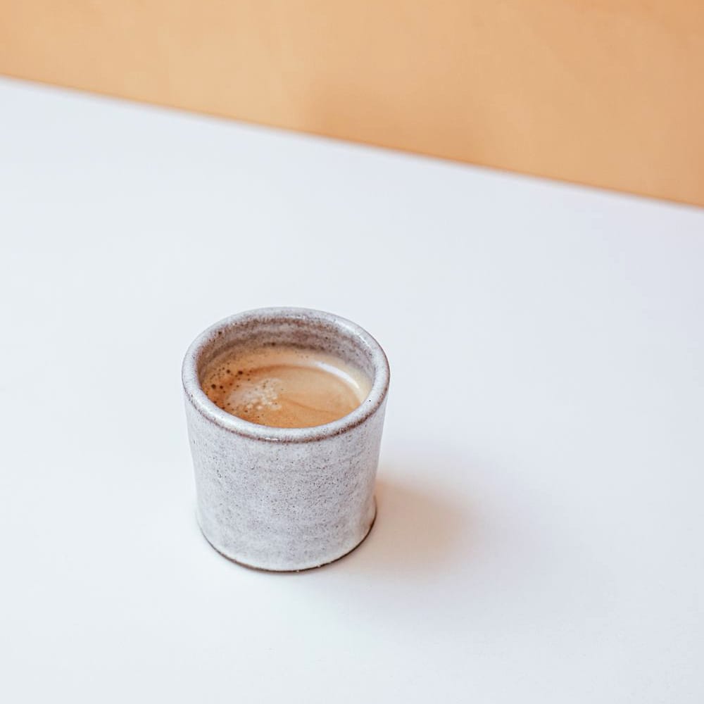 A takeaway coffee cup on a soft cream surface