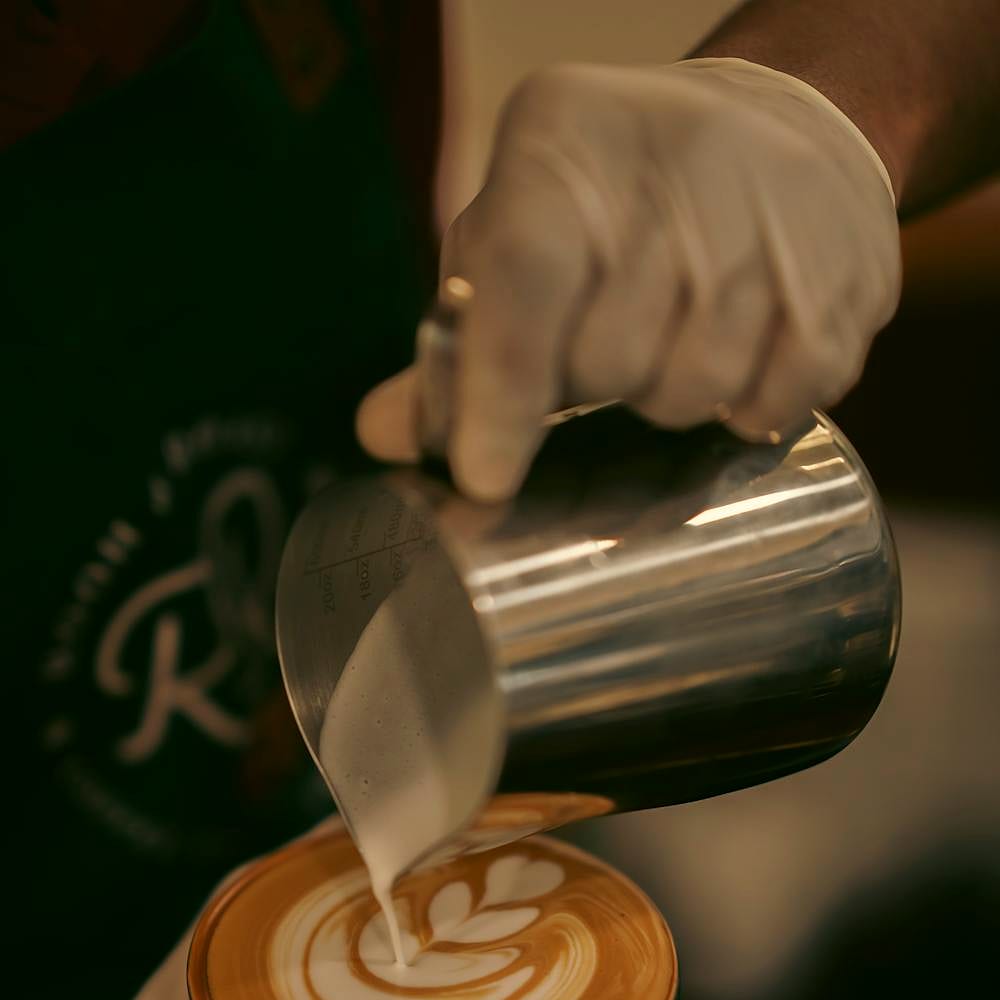 A barista finishing latte art on a specialty drink