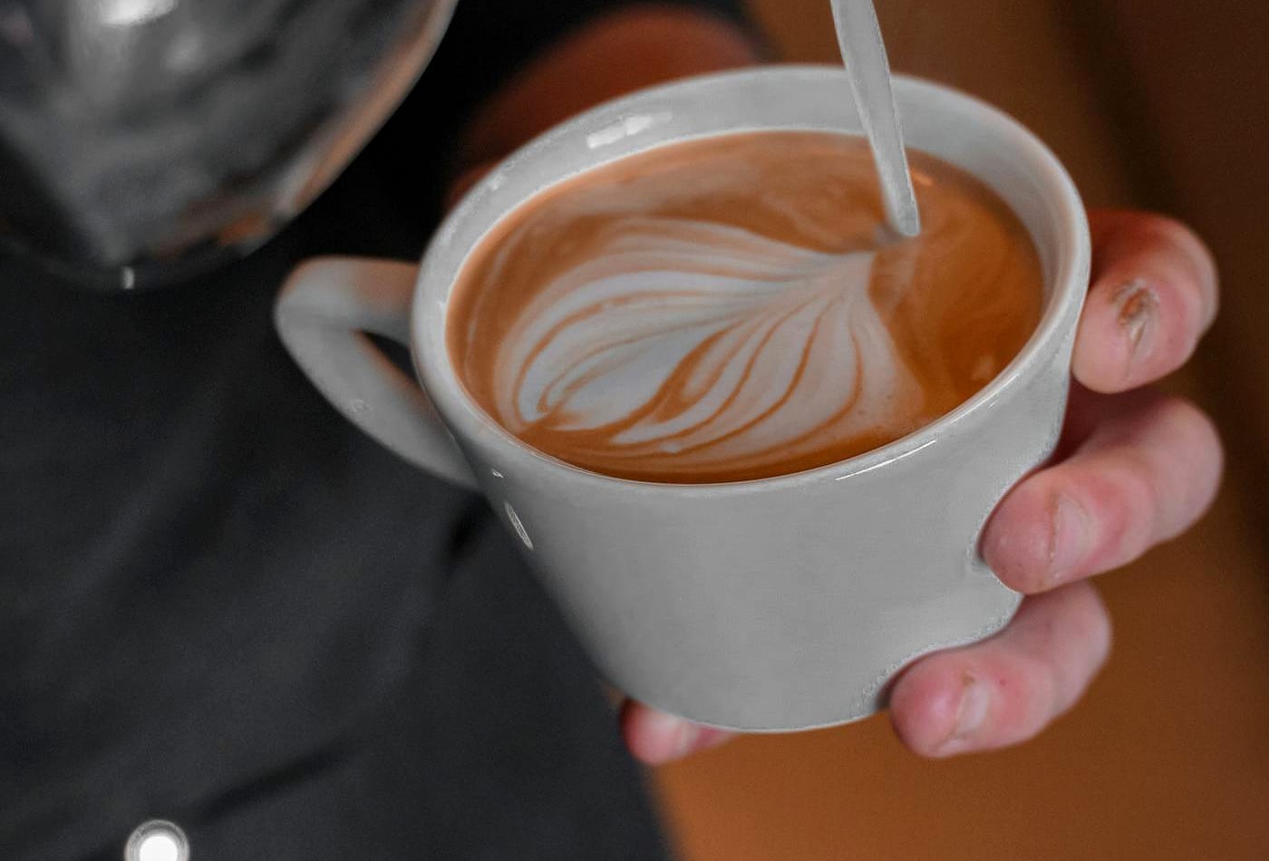 Steamed milk being poured into a fresh coffee