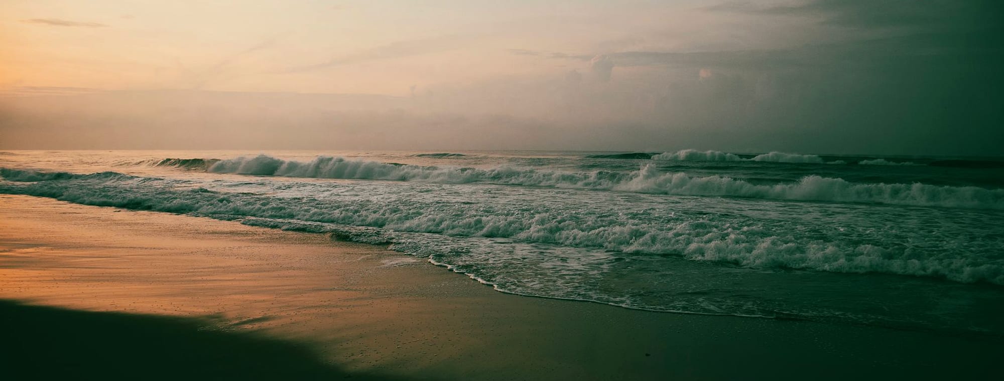 Soft morning surf rolling onto a Northern Beaches shoreline at dawn